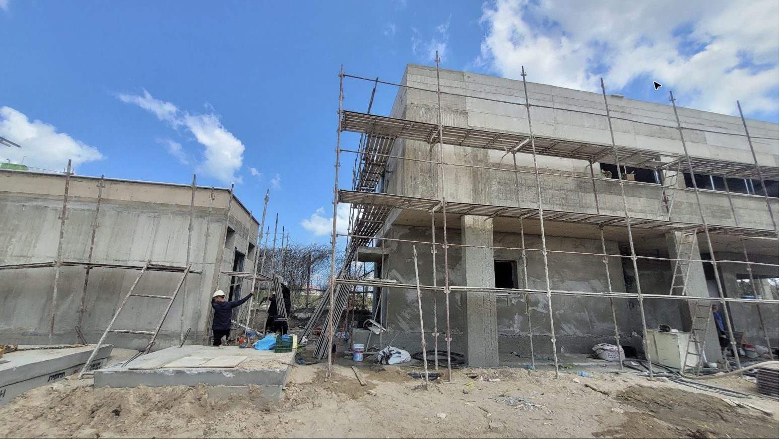 מבני בטון של עמדת שומרים וחדר חשמל בשלב הכנות לטיח, עם פיגומים היקפיים