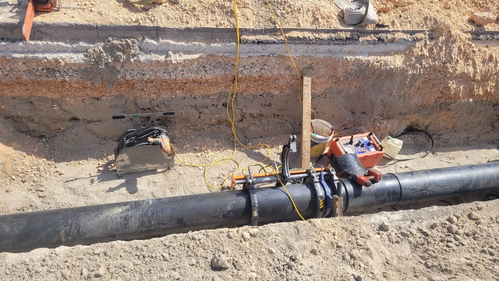 ריתוך פיוז'ן של צנרת מים בפוליאתילן בתעלת חפירה, עם ציוד ריתוך ומדידה